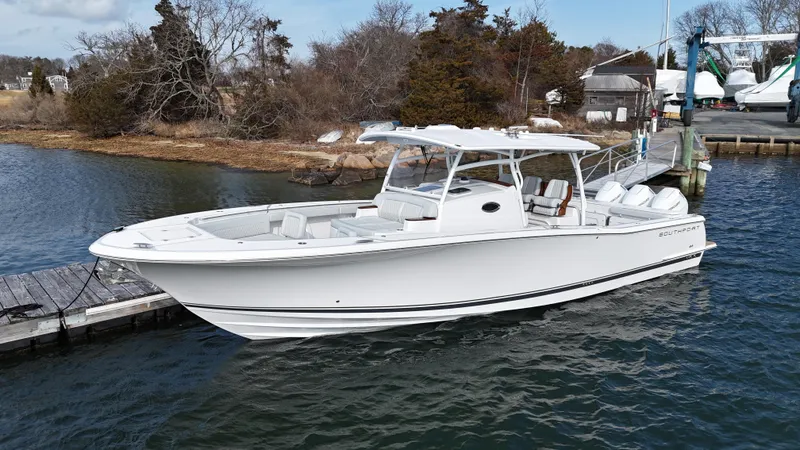 Slide: The Image of 2025 Southport 38 FE boat with rod holders and seating, docked by the water. - 38