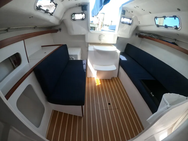 Slide: The Image of Interior of 2022 J Boats J/9 sailboat with wooden flooring and blue seating. - 19