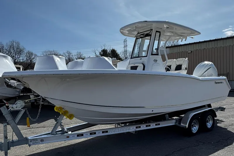 Slide: The Image of 2025 Tidewater 232 CC Adventure boat on trailer, parked outdoors under clear sky. - 1