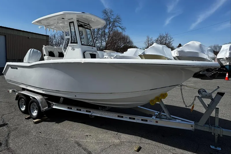 Slide: The Image of 2025 Tidewater 232 CC Adventure boat on trailer, parked outdoors under clear sky. - 2
