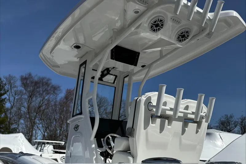Slide: The Image of 2025 Tidewater 232 CC Adventure boat with T-top and rod holders, under clear blue sky. - 22