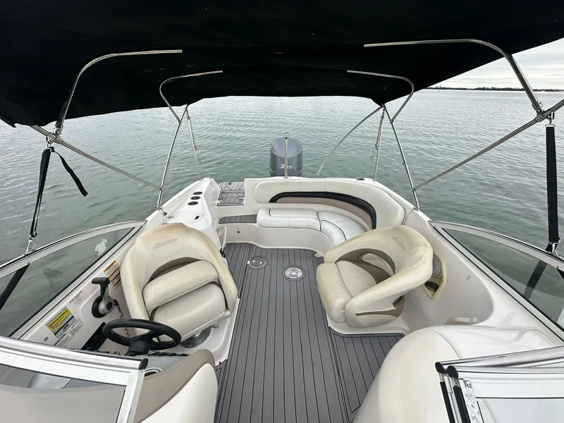 Slide: The Image of 2007 Hurricane SunDeck 237 OB boat interior with seating and canopy on calm water. - 8