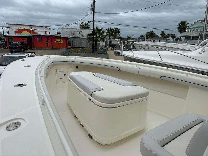 Slide: The Image of 2019 Mako 334 CC boat interior with seating and storage, docked under cloudy skies. - 7