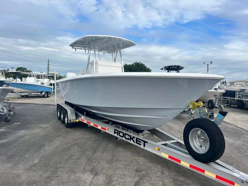 Slide: The Image of 2023 Contender 30T boat on a Rocket trailer, parked outdoors under a cloudy sky. - 2