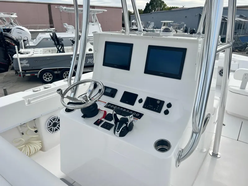 Slide: The Image of 2023 Contender 30T boat console with dual screens and steering wheel in a marina setting. - 8