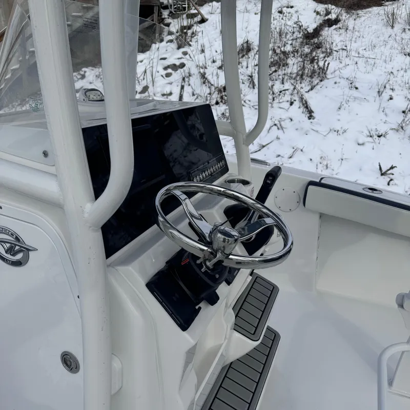 Slide: The Image of 2025 Tidewater 220 LXF boat helm with steering wheel and controls, snowy background. - 14