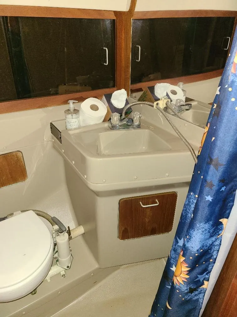 Slide: The Image of 1985 O'Day 35 yacht bathroom with sink, toilet, and nautical-themed shower curtain. - 13