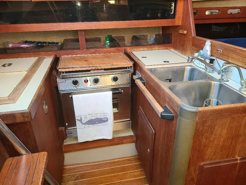 Slide: The Image of 1985 O'Day 35 sailboat galley with stove, sink, and wooden cabinetry. - 16