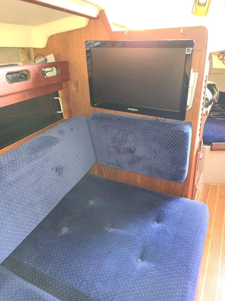 Slide: The Image of Interior of 1985 O'Day 35 sailboat with blue cushioned seating and mounted TV. - 18