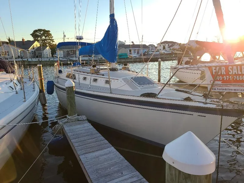 Slide: The Image of 1985 O'Day 35 sailboat docked at marina, sunset in background, for sale sign visible. - 6