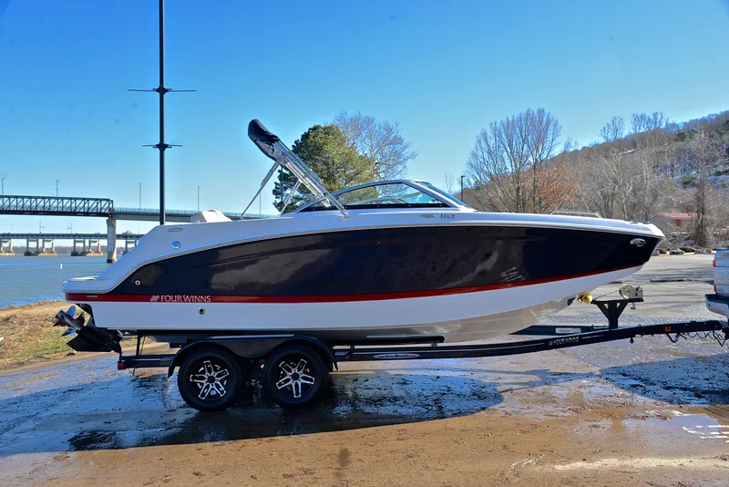 Slide: The Image of 2021 Four Winns HD3 boat on trailer by riverside, clear sky background. - 15