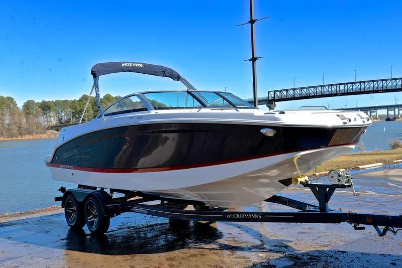 Slide: The Image of 2021 Four Winns HD3 boat on trailer by a river, under clear blue sky. - 16