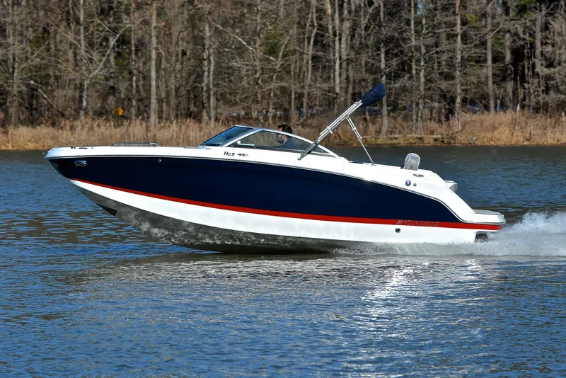 Slide: The Image of 2021 Four Winns HD3 boat cruising on a lake with forest background. - 2