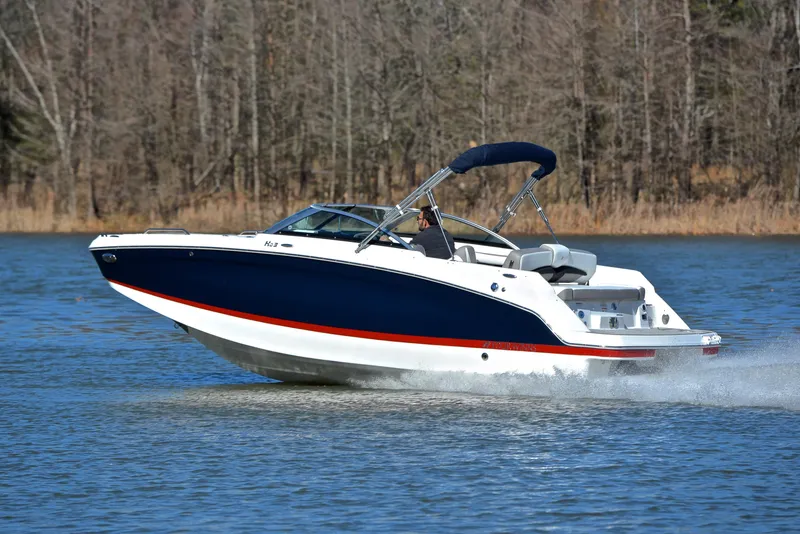 Slide: The Image of 2021 Four Winns HD3 boat cruising on a lake with forested background. - 4
