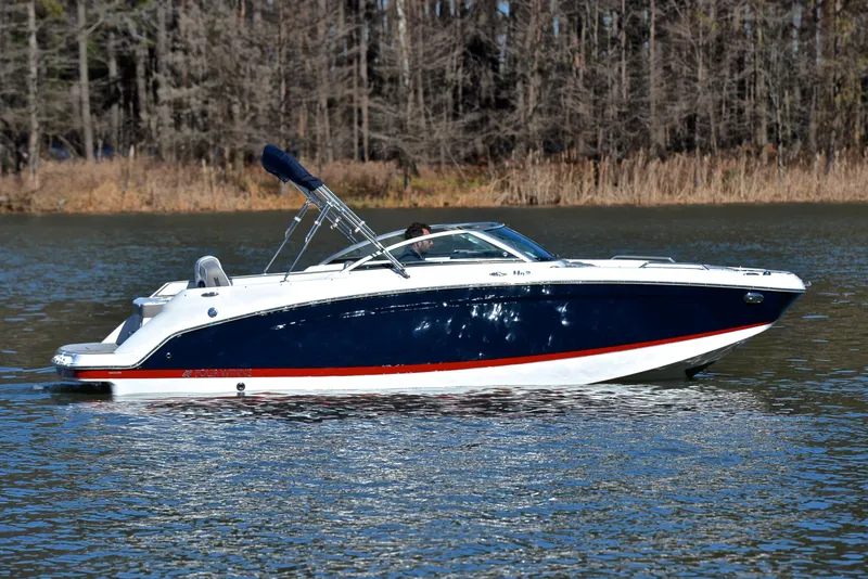 Slide: The Image of 2021 Four Winns HD3 boat cruising on a calm lake with forest background. - 7