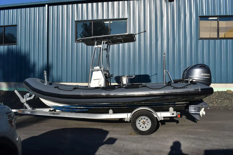 The Image of 2019 Ribcraft 6.5 boat on trailer, parked outside a blue building. - 0