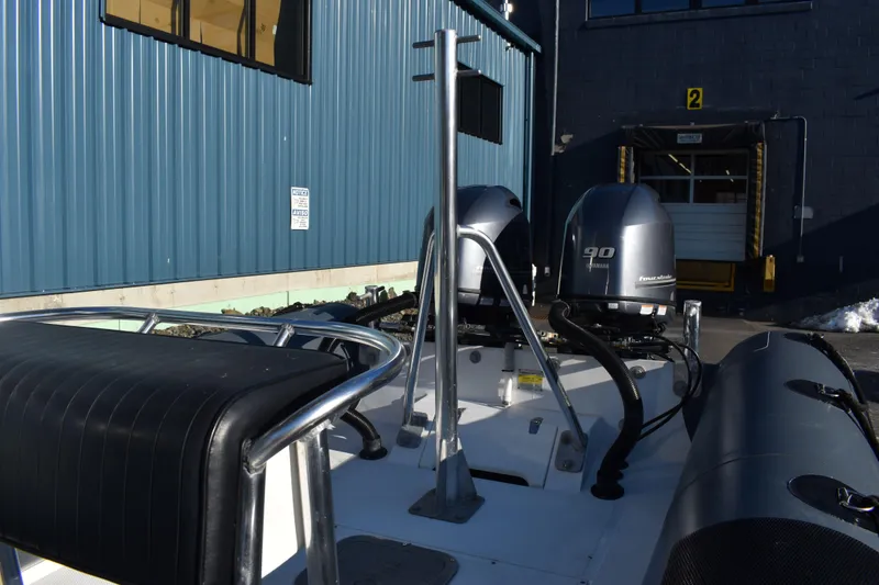Slide: The Image of Ribcraft 6.5 boat, 2019 model, with dual outboard motors, docked near a blue industrial building. - 2