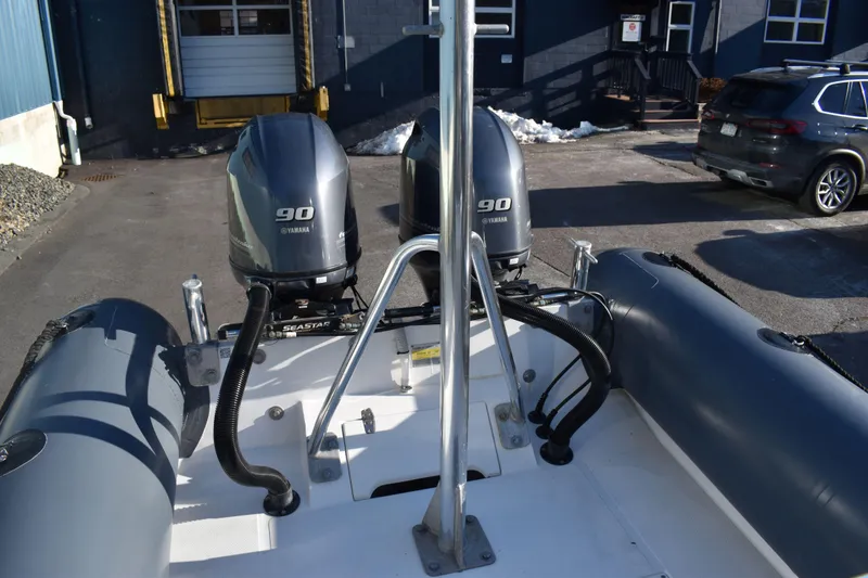 Slide: The Image of 2019 Ribcraft 6.5 boat with twin 90 horsepower engines in a parking area. - 6