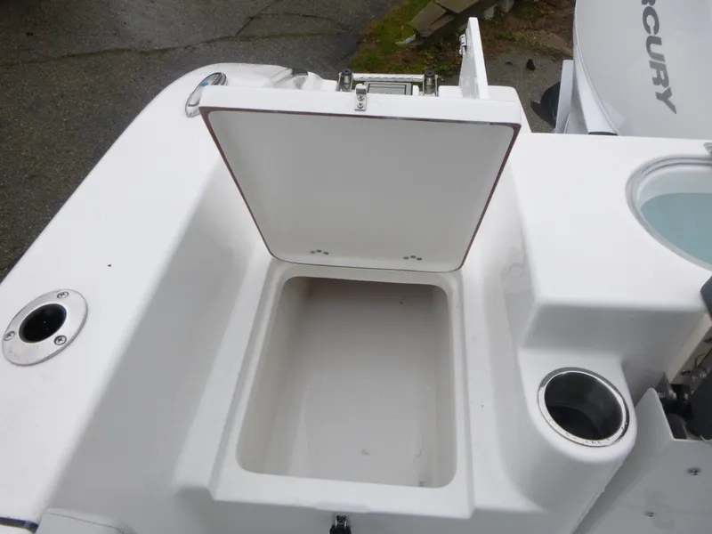 Slide: The Image of 2025 Sea Pro 242 Center Console boat storage compartment with open lid and cup holder. - 13