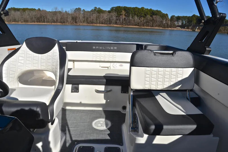 Slide: The Image of 2020 Bayliner VR5 boat interior with white and black seating, on a calm lake. - 18