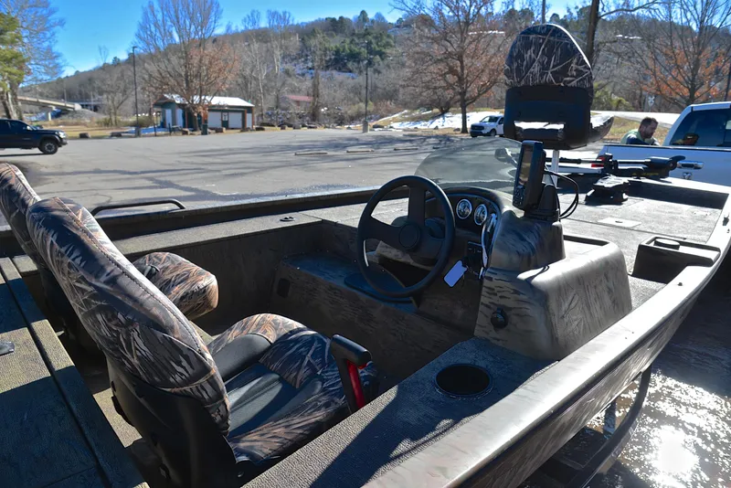 Slide: The Image of 2016 G3 Eagle 176 boat interior with camo seats and steering wheel, parked outdoors. - 19
