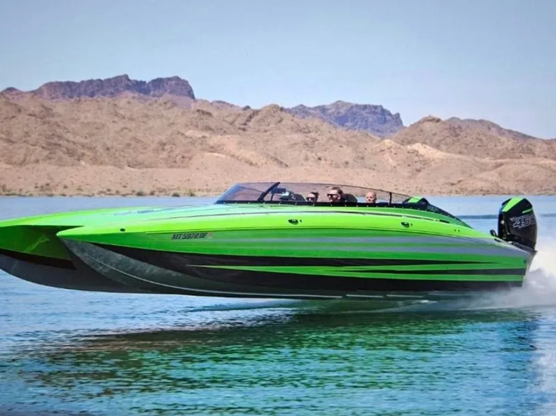 Slide: The Image of 2023 Daves Custom Boats M37R, vibrant green, speeding on a lake with mountainous backdrop. - 4