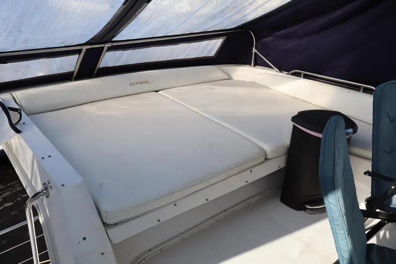 Slide: The Image of 2006 Bluewater Yachts 5200 interior with cushioned seating and covered deck area. - 12