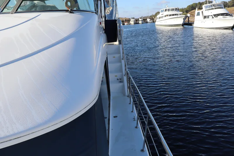 Slide: The Image of 2006 Bluewater Yachts 5200 on calm water, docked alongside other boats. - 3