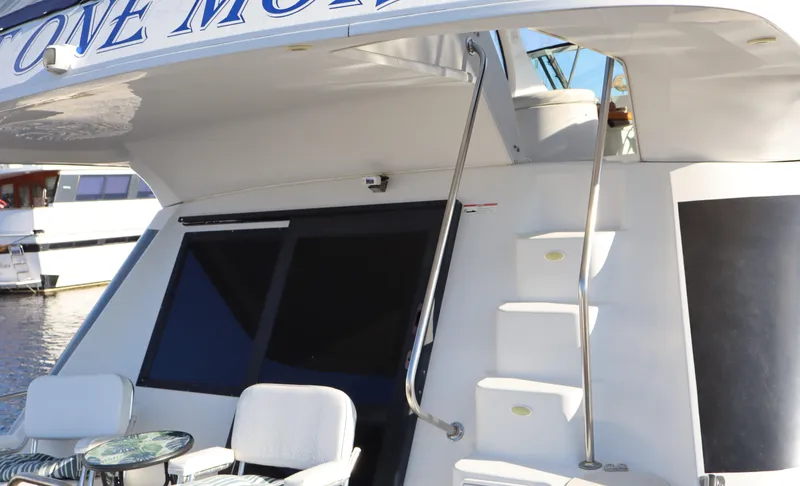 Slide: The Image of 2006 Bluewater Yachts 5200, rear view with seating and stairs, docked by the water. - 5