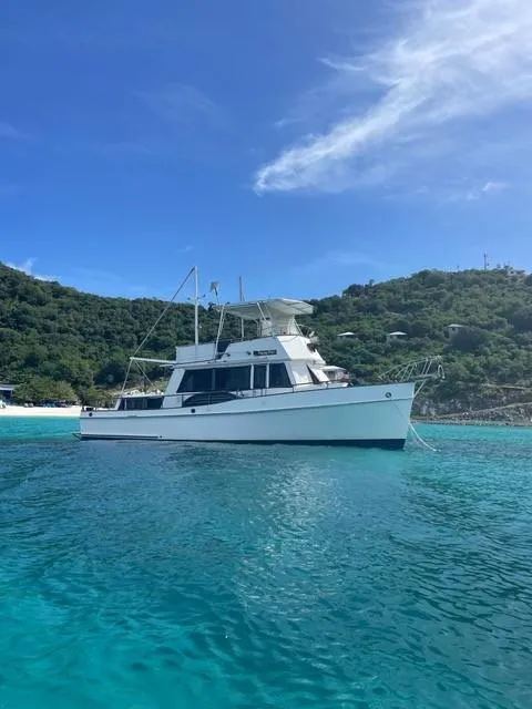 The Image of 1986 Grand Banks 42 Classic yacht on clear turquoise water near a lush green island. - 0