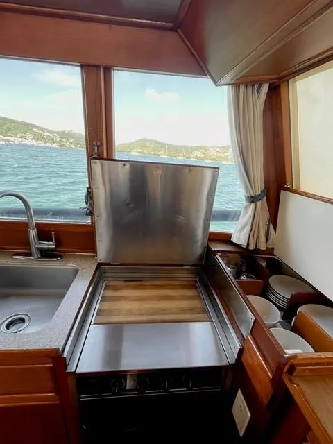Slide: The Image of 1986 Grand Banks 42 Classic yacht kitchen with ocean view, featuring sink and stove. - 14