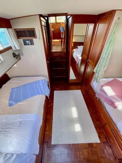 Slide: The Image of 1986 Grand Banks 42 Classic cabin interior with twin beds, wood paneling, and natural light. - 15