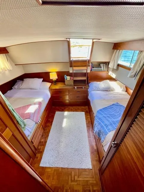 Slide: The Image of 1986 Grand Banks 42 Classic cabin with twin beds, wooden interior, and natural light. - 17