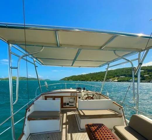 Slide: The Image of 1986 Grand Banks 42 Classic yacht interior with seating, canopy, and scenic ocean view. - 26