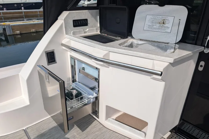 Slide: The Image of 2020 Regal 38 Grande Coupe yacht kitchenette with open fridge and storage compartments. - 8