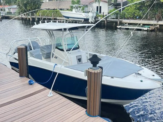The Image of 2019 Wellcraft 262 F CC boat docked by a waterfront, featuring a sleek design and blue hull. - 1