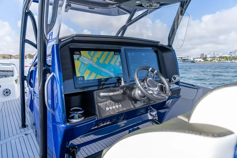 Slide: The Image of 2024 Nor-Tech 390 Sport boat dashboard with navigation screens and steering wheel. - 13