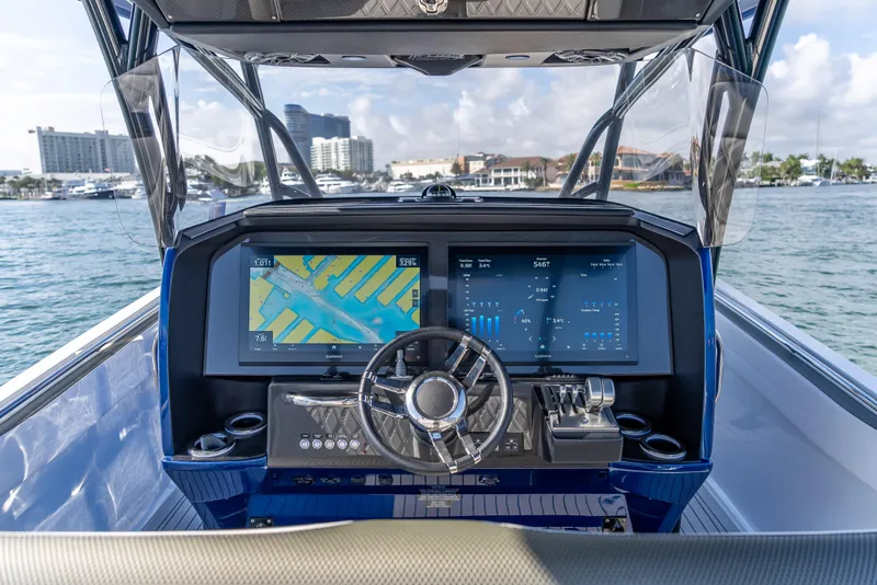 Slide: The Image of 2024 Nor-Tech 390 Sport boat dashboard with dual screens and steering wheel, on water. - 20