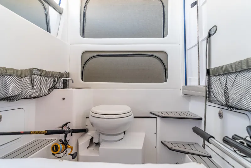 Slide: The Image of 2024 Nor-Tech 390 Sport boat interior with toilet and fishing gear storage. - 30