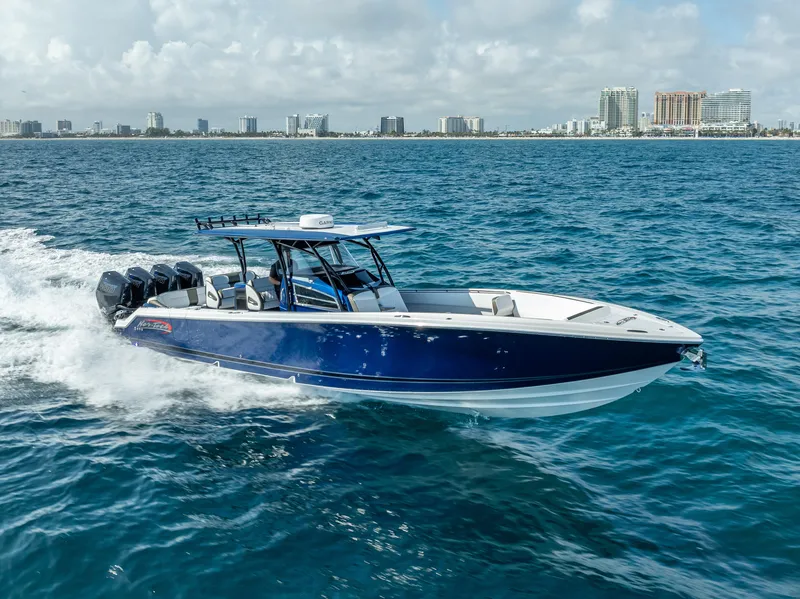 Slide: The Image of 2024 Nor-Tech 390 Sport boat cruising on open water with city skyline in background. - 35