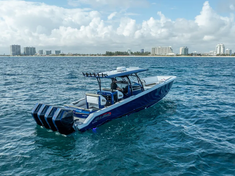 Slide: The Image of 2024 Nor-Tech 390 Sport boat cruising on open water with city skyline in background. - 48