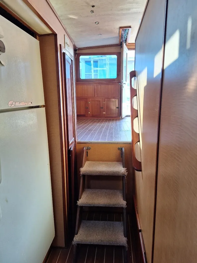 Slide: The Image of Interior view of a 1970 Hatteras 45 Sportfish yacht, featuring wooden flooring and steps. - 18