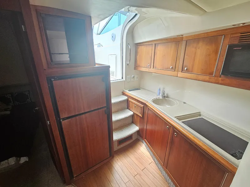 Slide: The Image of 2008 Riviera M470 yacht interior with wooden cabinets, compact kitchen, and stairs. - 17
