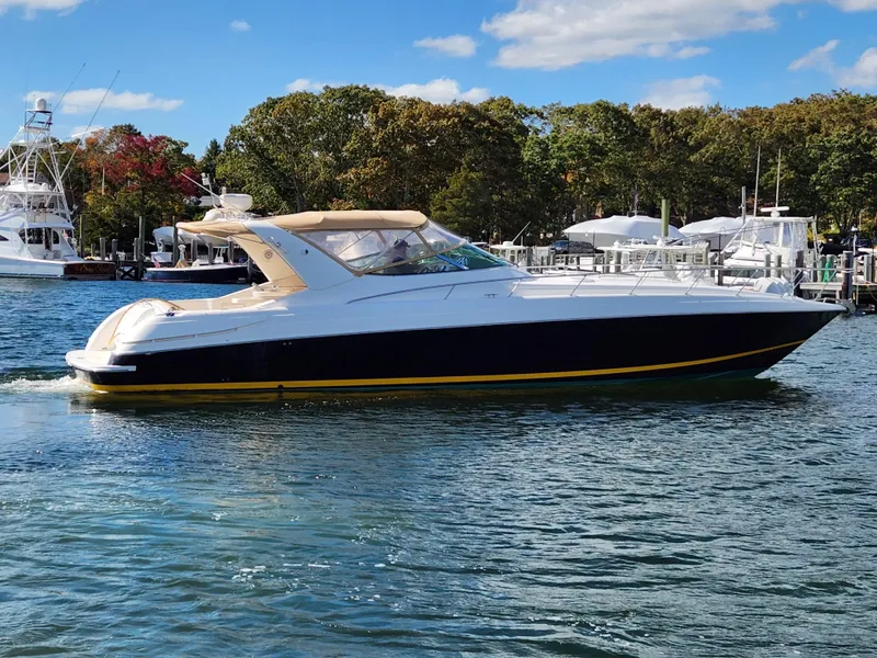 Slide: The Image of 2008 Riviera M470 yacht on calm water, surrounded by trees and other boats. - 2