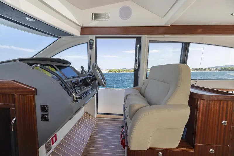 Slide: The Image of Interior of 2025 Nimbus 405 Flybridge yacht, featuring helm and seating with ocean view. - 13