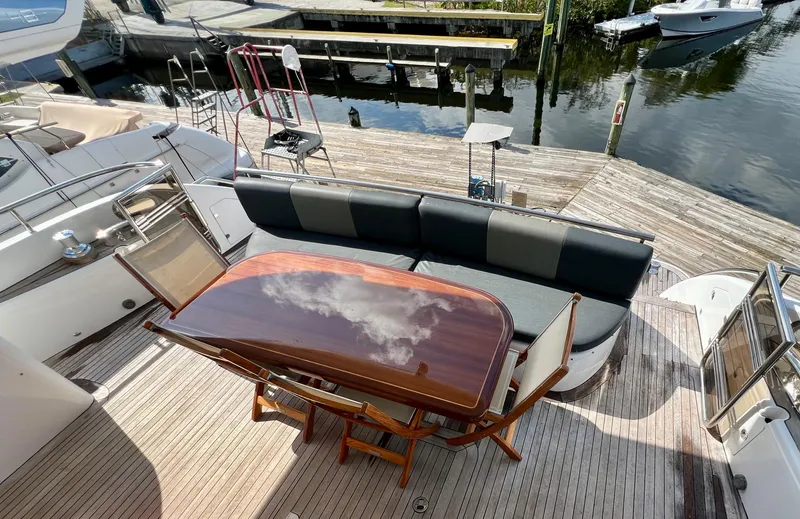 Slide: The Image of 2008 Viking Sport Cruisers 70 Motor Yacht deck with seating and table, docked by the water. - 18