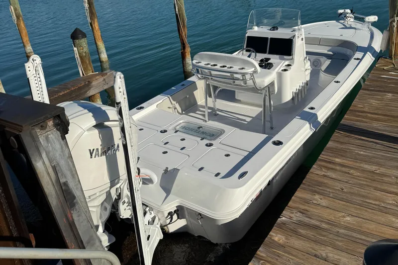 Slide: The Image of 2025 Contender 26 Bay boat on lift, featuring Yamaha engine, docked by tropical waterfront. - 2