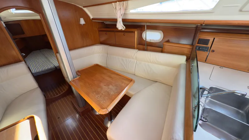 Slide: The Image of Interior of 2004 Jeanneau Sun Fast 35 sailboat with wooden table and seating area. - 13