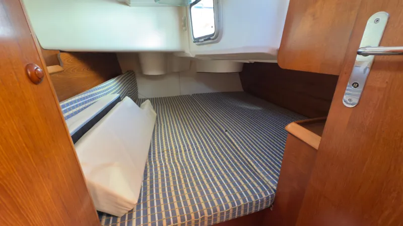 Slide: The Image of 2004 Jeanneau Sun Fast 35 cabin with striped bedding and wooden interior. - 16