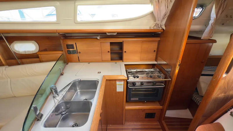 Slide: The Image of Interior of 2004 Jeanneau Sun Fast 35 yacht, featuring a compact kitchen with sink and stove. - 18